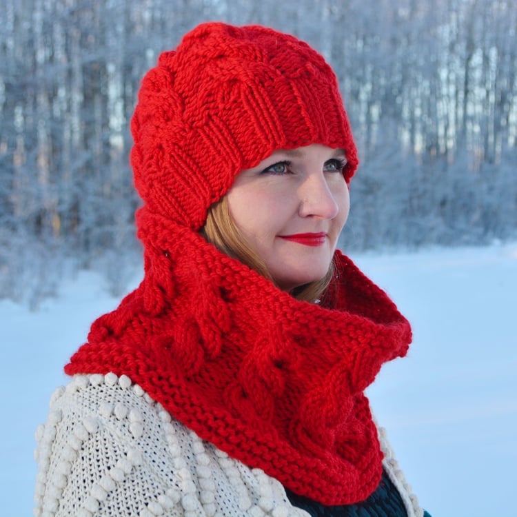 Talena wears a red Prairie Twist chunky cable-knit beanie & cowl and looks off-camera.