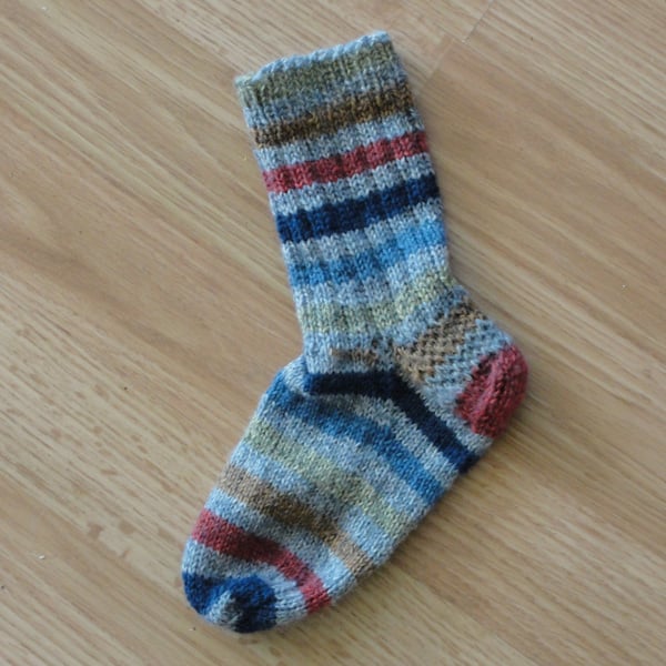 Flat lay of a young childs knit sock with ribbed leg and stockinette foot, decreased toes, and eye-of-partridge heel.