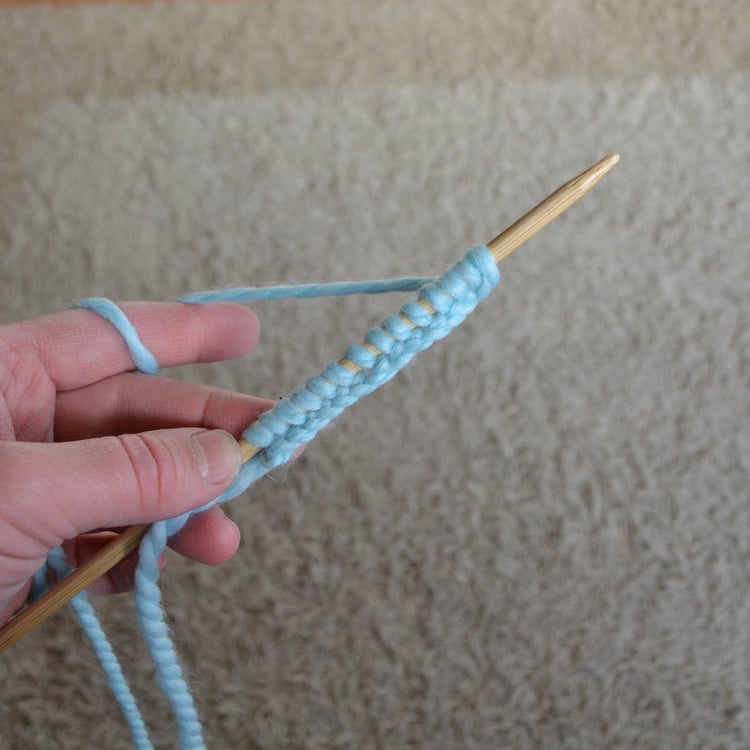 A row of knit stitches cast onto a needle.