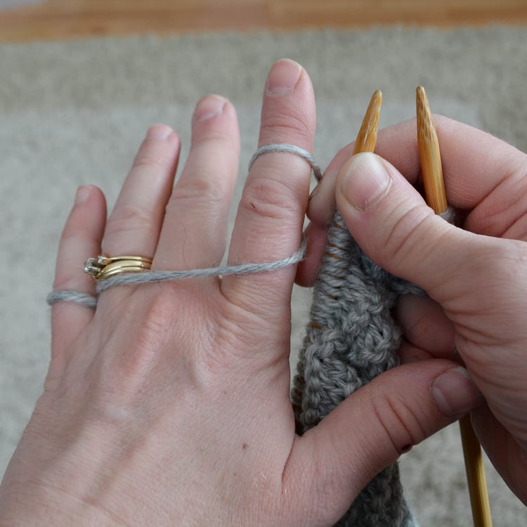 Hands wrapped in yarn for knitting.