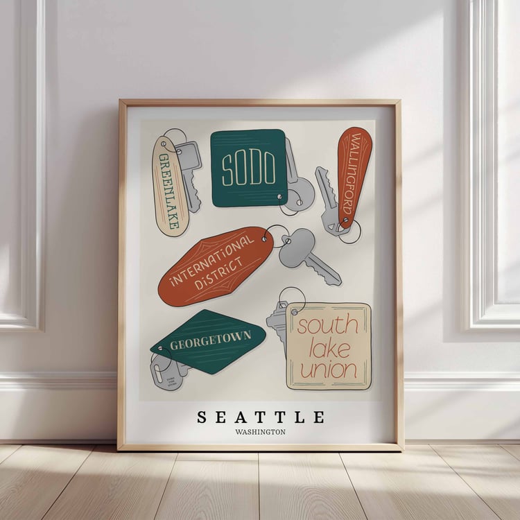 A framed picture of Seattle neighborhoods drawn in various lettering styles on key fobs. Artwork has a orange, green and beige color scheme