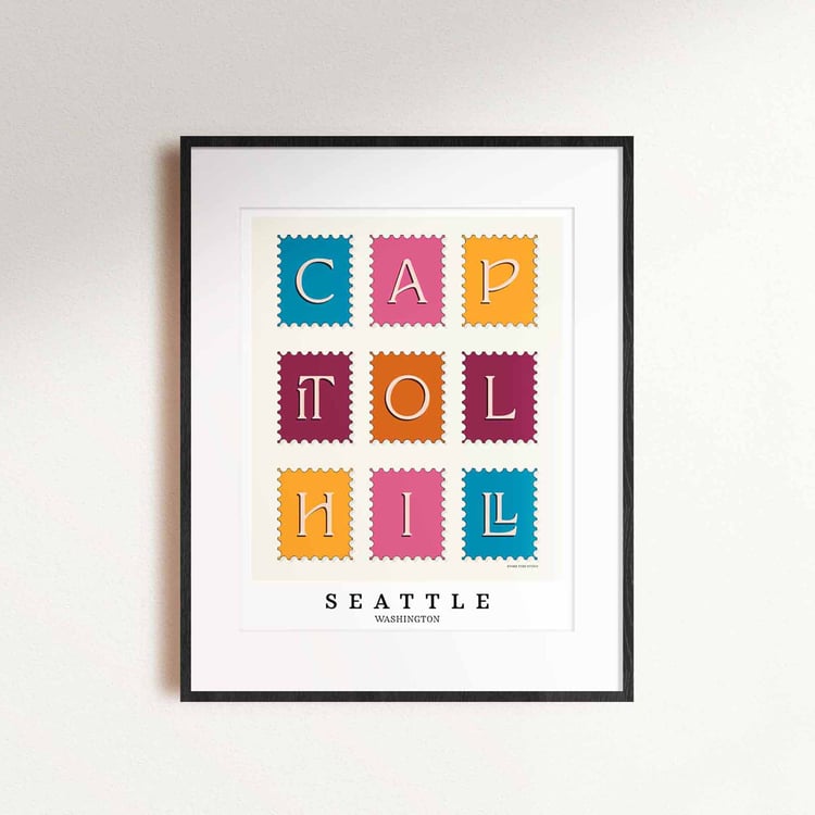 A framed picture of postage stamps featuring the Capitol Hill neighborhood in Seattle, Washington drawn in a unique lettering style. Artwork has a bright blue, orange and purple color scheme