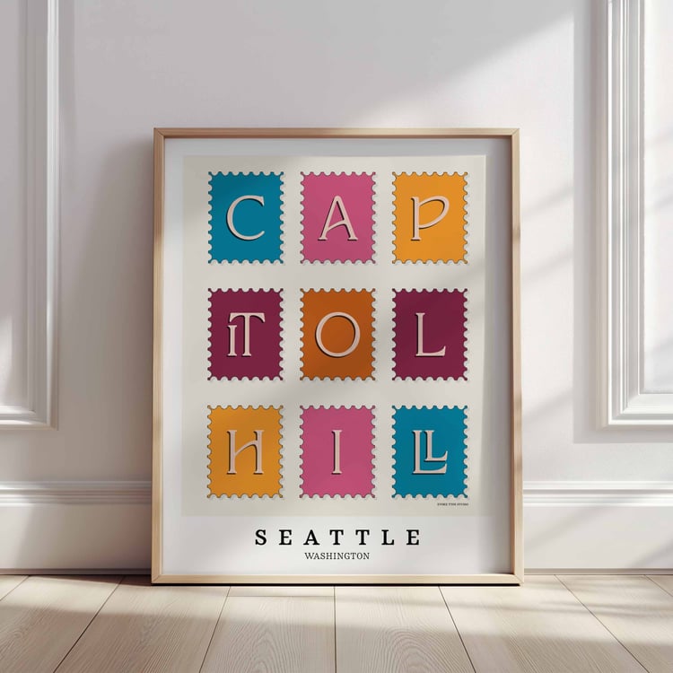 A framed picture of postage stamps featuring the Capitol Hill neighborhood in Seattle, Washington drawn in a unique lettering style. Artwork has a bright blue, orange and purple color scheme