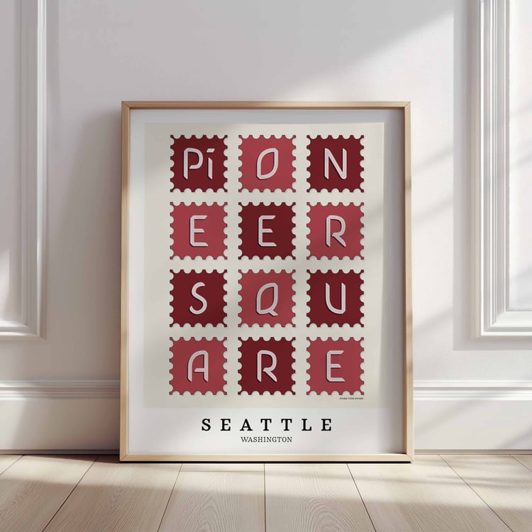 A framed picture of postage stamps featuring the Pioneer Square neighborhood in Seattle, Washington drawn in a unique lettering style. Artwork has a red and white color scheme