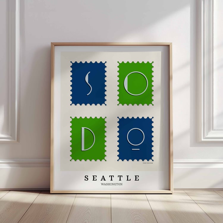 A framed picture of postage stamps featuring the SoDo neighborhood in Seattle, Washington drawn in a unique lettering style. Artwork has a bright blue and green color scheme