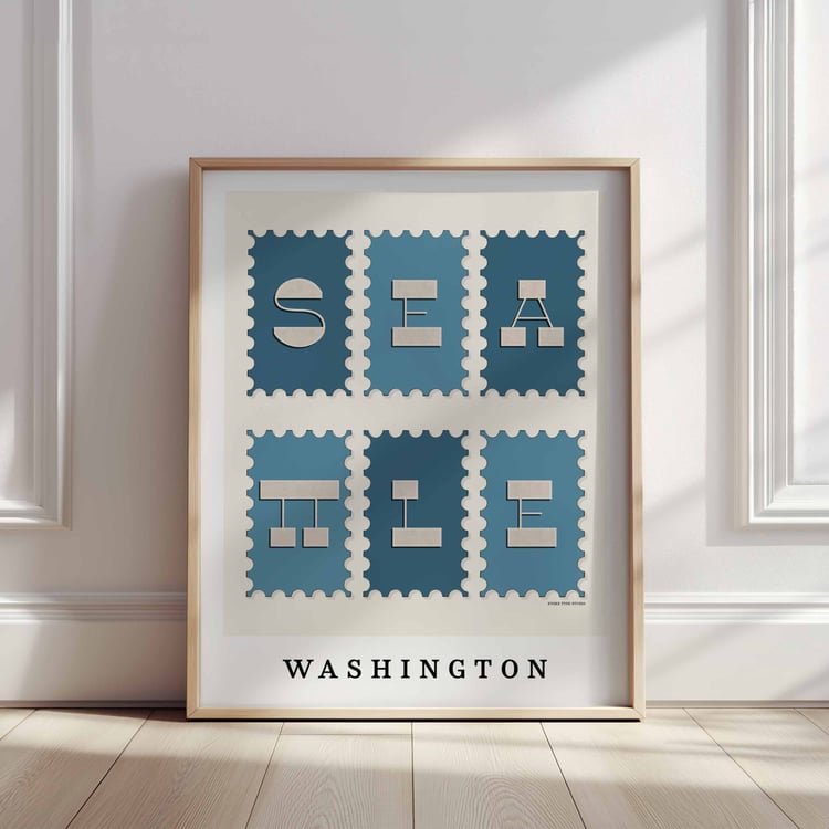 A framed picture of postage stamps featuring Seattle, Washington drawn in a unique lettering style. Artwork has a blue and beige color scheme