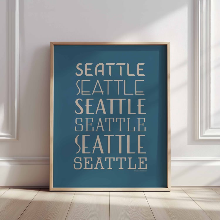 A framed picture of the word "Seattle" drawn in various lettering styles. Artwork has a blue and beige color scheme
