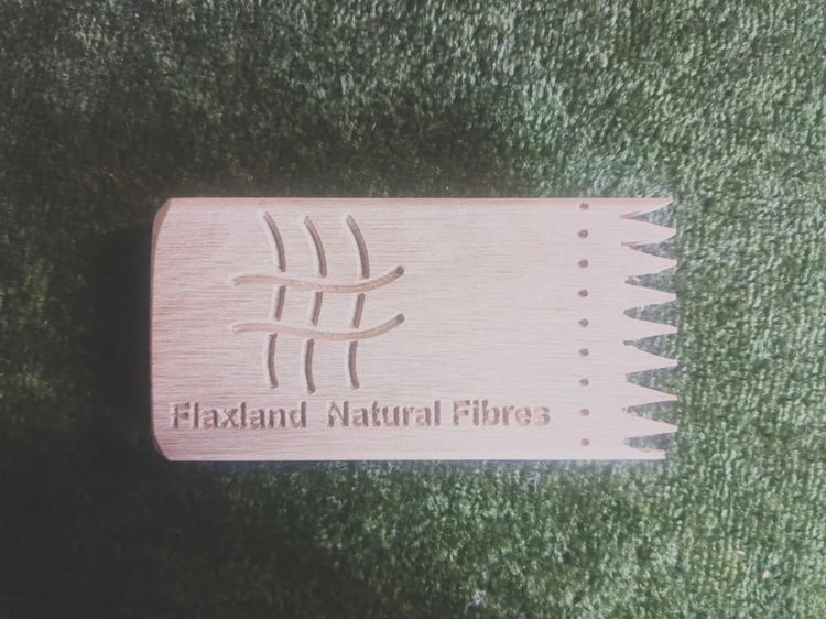 A multi-function flax processing tool. It is a wooden block with triangular teeth at one end. It has been engraved with the Flaxland Natural Fibres logo of crossed wavy lines representing woven fibres,