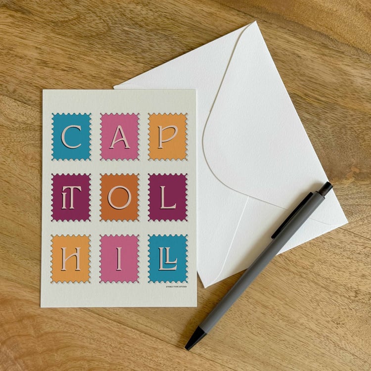 A colorful notecard sitting on a table with a white envelope and pen.