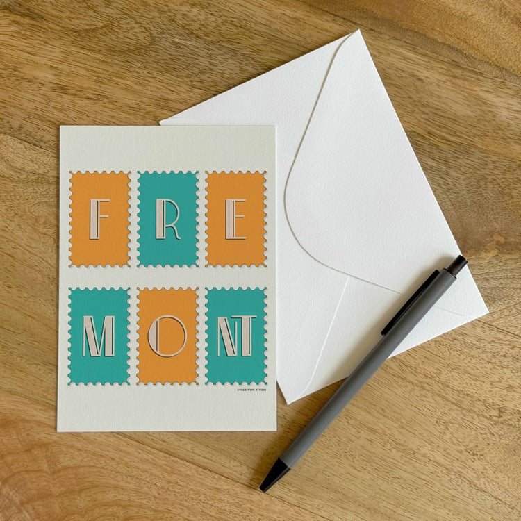 A colorful notecard sitting on a table with a white envelope and pen.