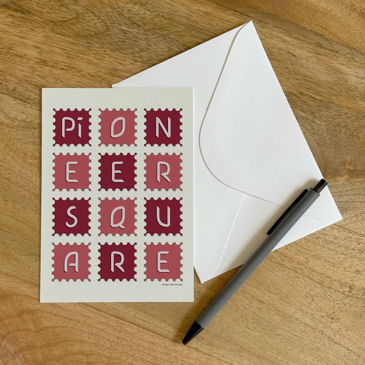 A colorful notecard sitting on a table with a white envelope and pen.