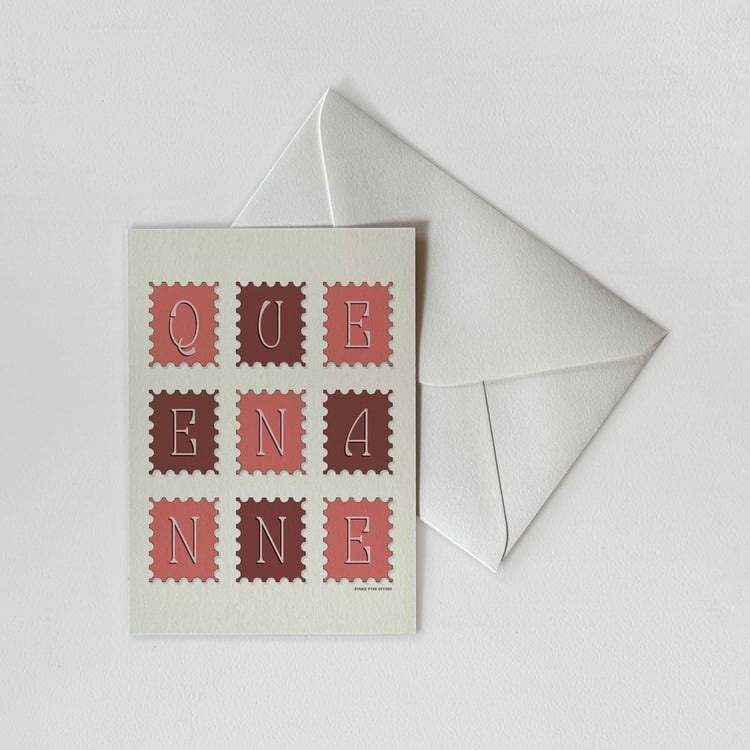 A notecard of postage stamps featuring the Queen Anne neighborhood in Seattle, Washington drawn in a unique lettering style with a white envelope. Artwork has a pink and burgundy color scheme