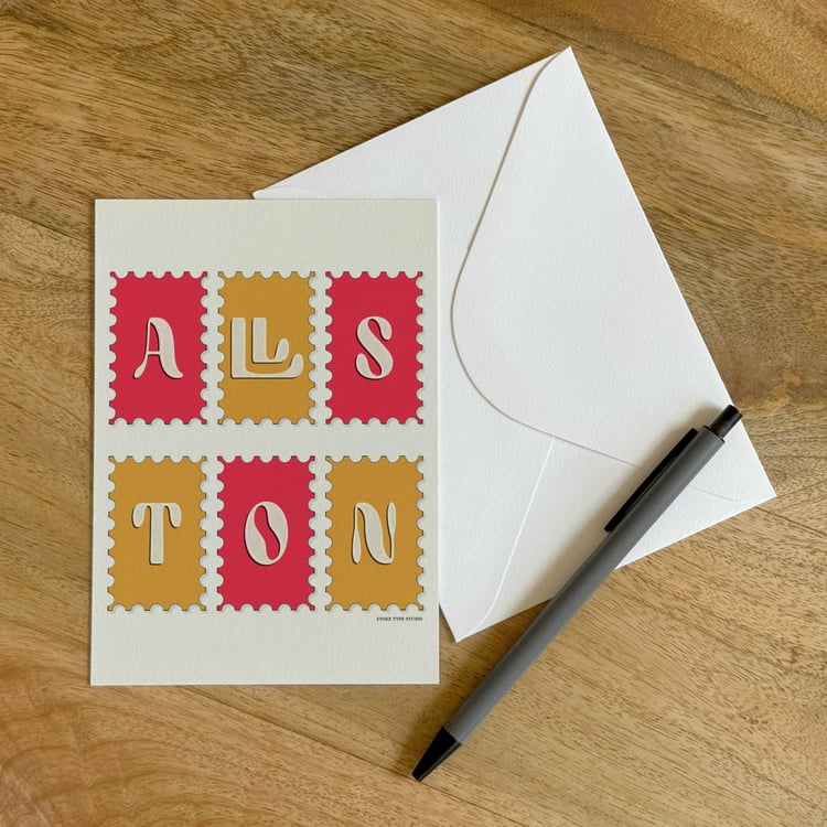 A colorful notecard sitting on a table with a white envelope and pen.
