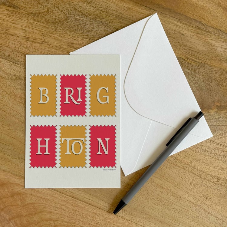 A colorful notecard sitting on a table with a white envelope and pen.