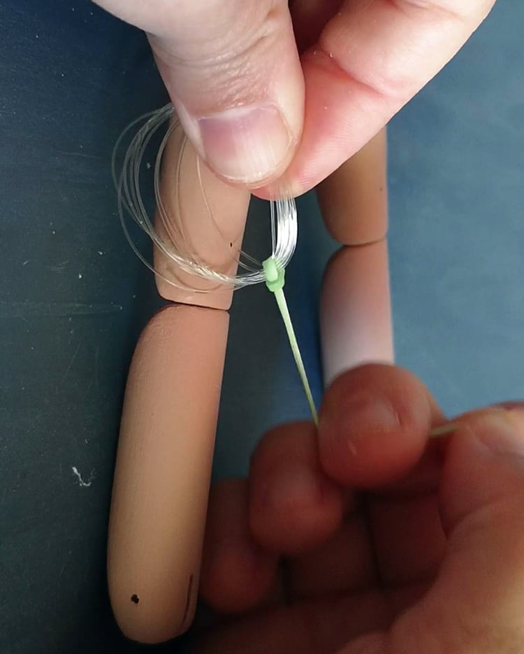Attaching fishing line to a marionette knee joint – DIY puppet stringing process.