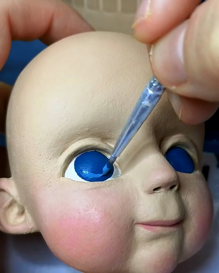 Painting details on a marionette head – adding blue iris to the puppet’s eye.