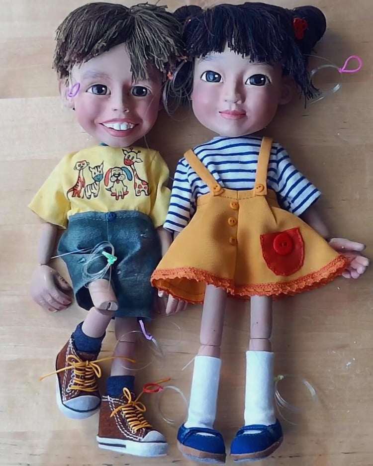 Two fully dressed marionettes, shoes included, not yet strung on their controllers – handmade puppet crafting in progress.
