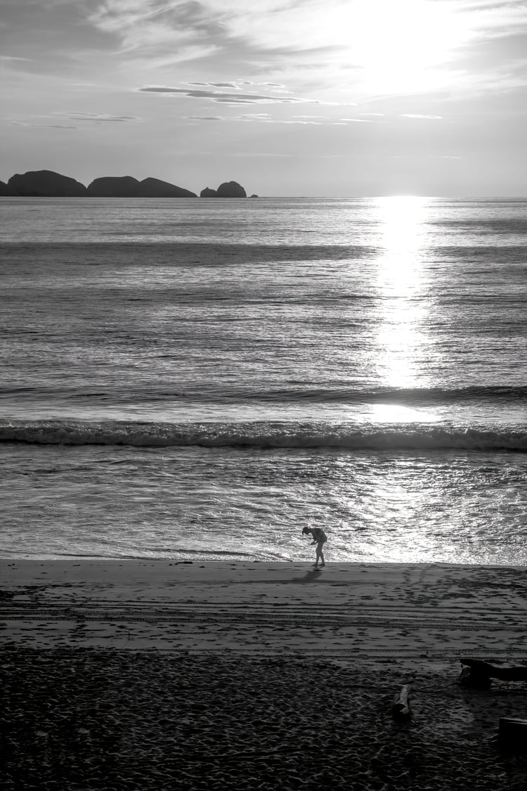 black and white sunset, lone figure beach photo, moody seascape print, silhouette at sunset, dramatic coastal art, fine art black and white, storytelling beach photo, contemplative ocean scene, monochrome wall art, minimalist beach silhouette
