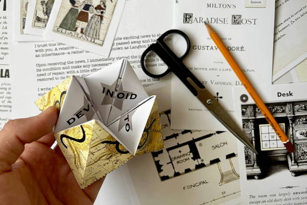 A player's hand holding a folded paper puzzle, demonstrating the hands-on, tactile gameplay of the DIY escape room 'The Secret of Langton Manor,' with scissors and clues in the background.