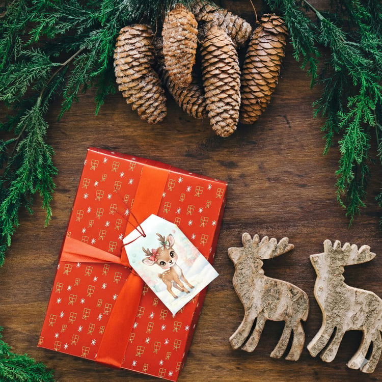 Printable woodland animal Christmas tag on red gift box with pinecones and greenery.