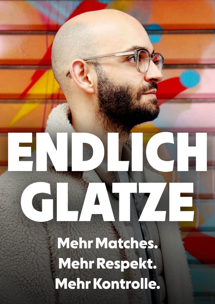 Selbstbewusster Mann mit gepflegter Glatze und Bart zeigt lächelnd auf seinen Kopf. Text: Schluss mit Haarausfall - Endlich Glatze in 7 Schritten