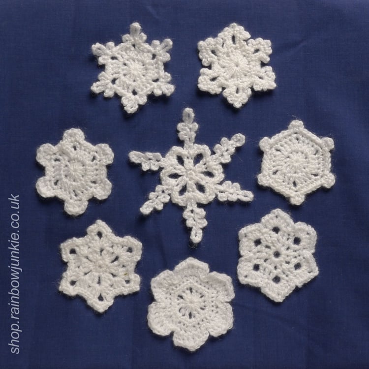 All eight snowflakes made in white DK acrylic on a dark blue background.