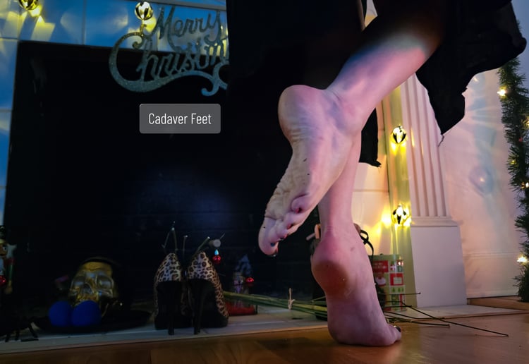 a pale feet tiptoeing across a hardwood floor in front of a fireplace