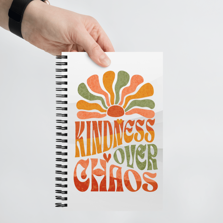 Spiral notebook with soft-touch cover featuring the phrase “Kindness Over Chaos” in retro typography.