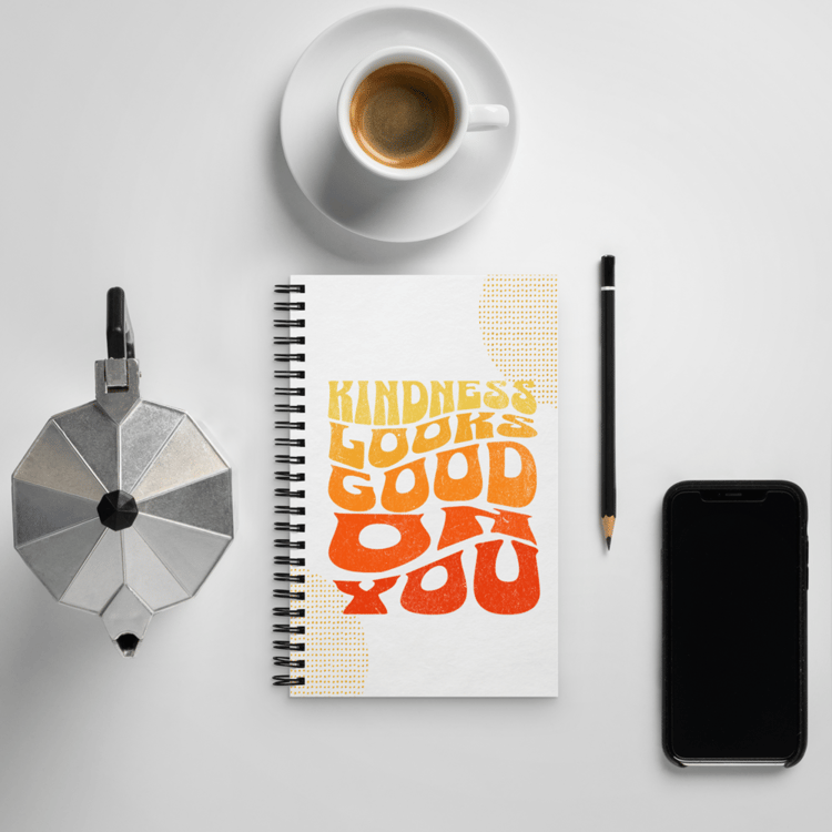 Spiral notebook with retro lettering that reads “Kindness Looks Good On You.”