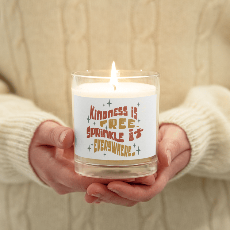 Glass soy candle with retro text that reads “Kindness is Free, Sprinkle it Everywhere.”