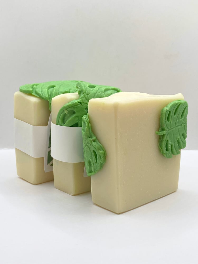 Handmade white soap draped with a green soap monstera leaf