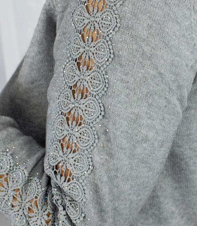 Grauer Pullover mit feiner Spitzenborte und Perlenverzierungen an den Ärmeln.