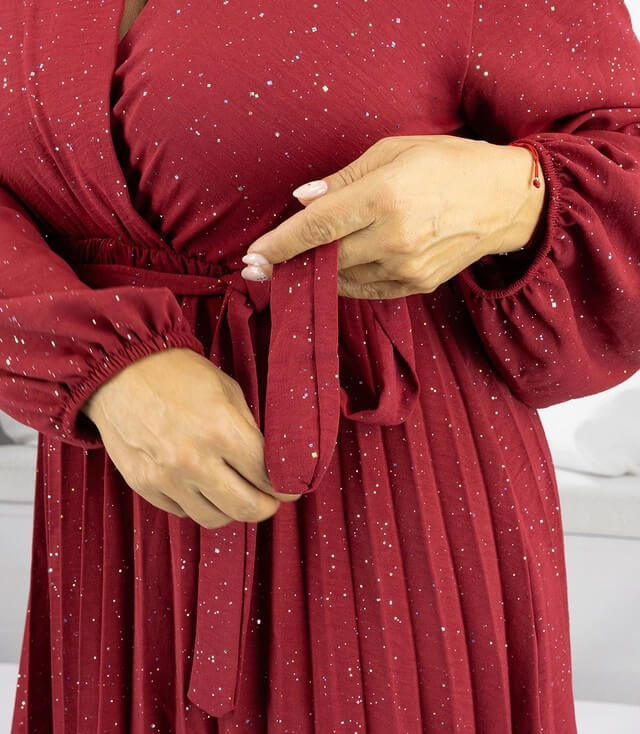 Detailaufnahme eines roten Kleides mit Glitzer, das an der Taille gebunden wird.