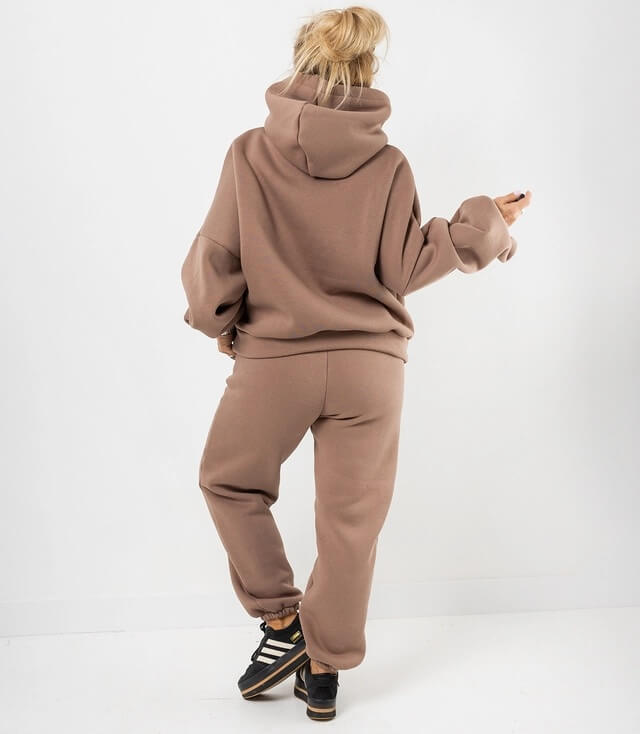Rückansicht eines braunen Sweatsets mit Kapuze und lockerer Passform, kombiniert mit Sneakern.