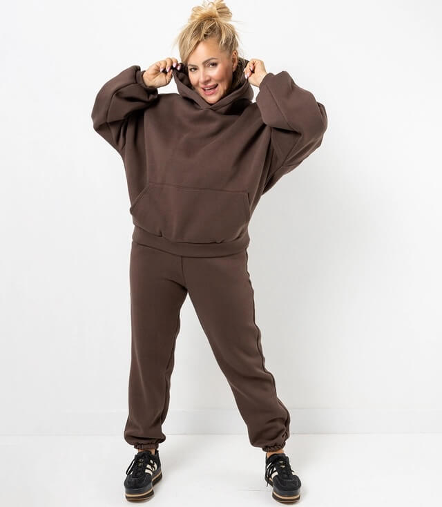 Damen-Sweatanzug in Braun, bestehend aus hoodie und Jogginghose, lässiger Schnitt, Model mit Kapuze.