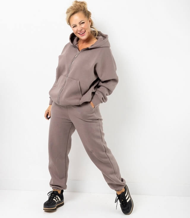 Jogger in Braun, bestehend aus lässiger Jacke und Jogginghose mit Taschen, kombiniert mit sportlichen Schuhen.