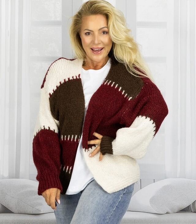 Frau in gestreifter Strickjacke in Rot, Braun und Beige, mit lässigem Oberteil und Jeans.