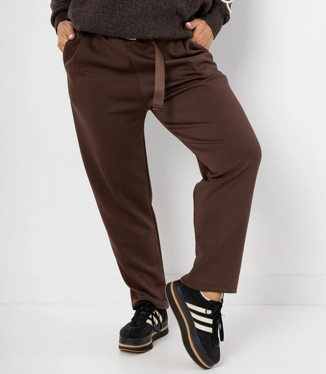 Braune Freizeithose mit schmalem Schnitt, seitlichen Taschen und bequemem Gummizug. Kombiniert mit Sneakers.