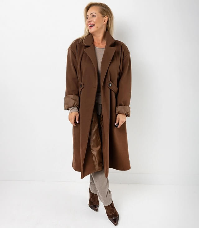 Eleganter brauner Mantel mit Gürtel und umgeschlagenen Ärmeln, getragen von einer fröhlichen Frau.