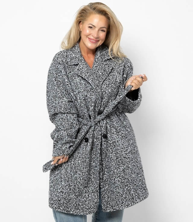 Frau trägt einen Oversize Boucle Mantel grau meliert mit Revers Kragen und Bindegürtel.