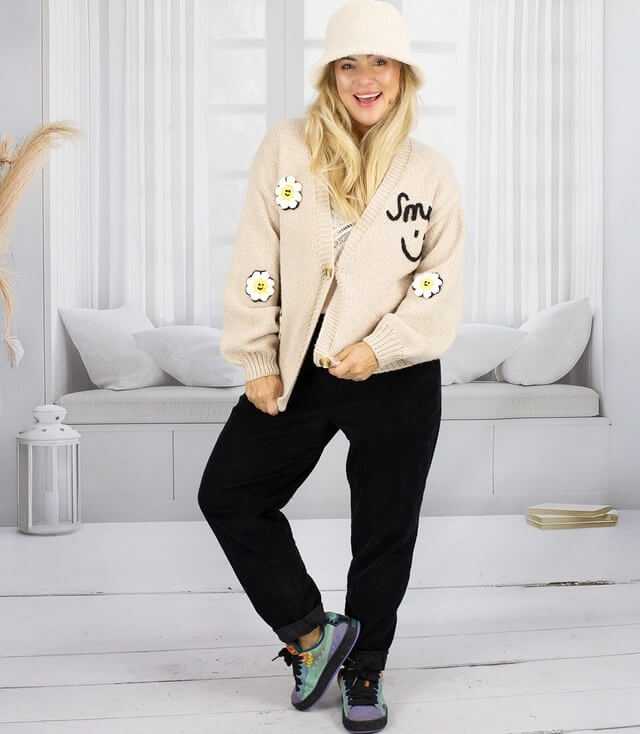 Modische, beige Strickjacke mit Blumenapplikationen und lässiger Passform, kombiniert mit bequemen Hosen.