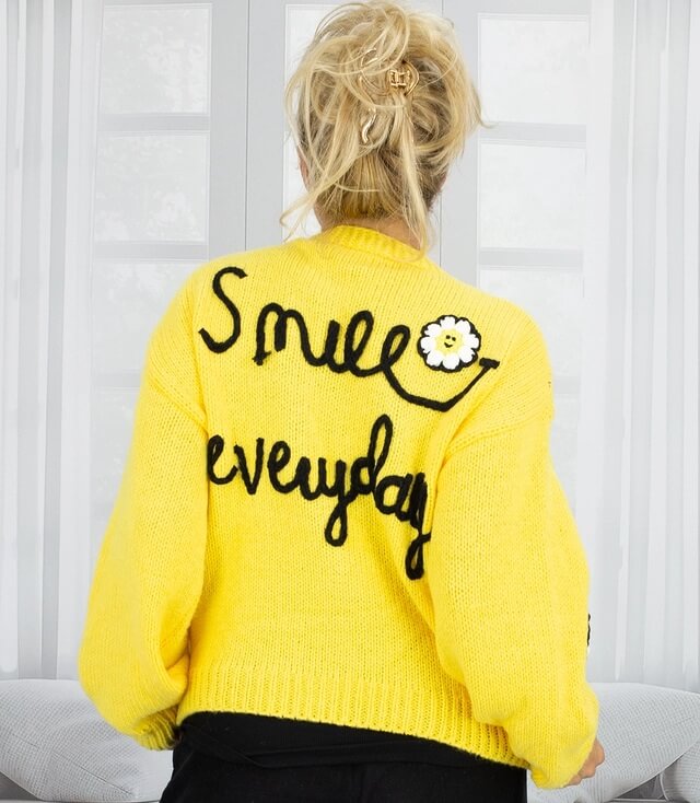 Gelber Pullover mit Rückenschriftzug "Smile everyday" und stylischem Blumenmotiv.