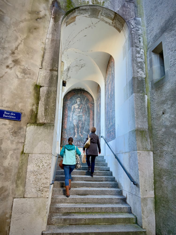 Two people walking in front of the Poncet Mosaics (Les Mosaïques de Poncet) in Geneva Old Town, Switzerland