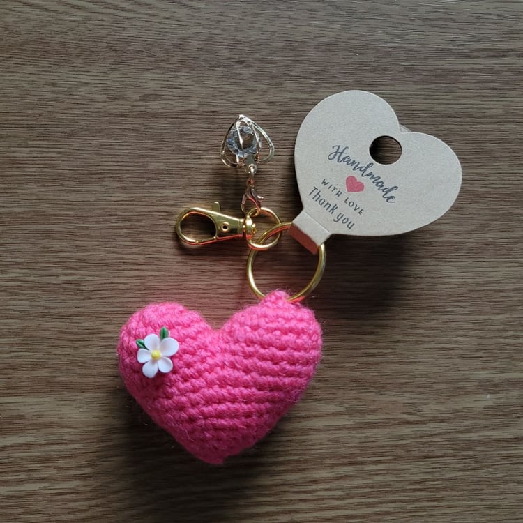 Crochet pink heart keyring with crystal charm and gold clasp on wooden background