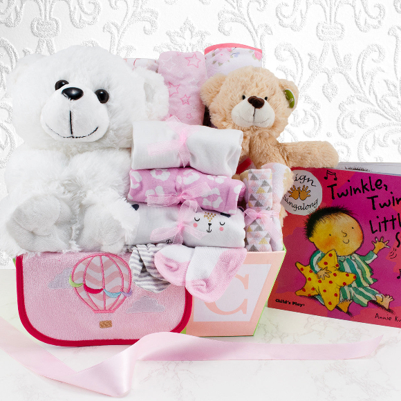 Baby gift basket with teddy bears, blankets, and a book on a white background