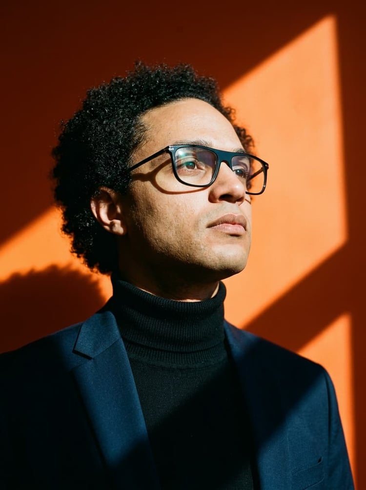 Portrait professionnel de signature de Benjamin Azika-Eros, Préparateur Mental et Expert en Performance Biologique, posant dans son cockpit stratégique avec un regard déterminé vers l'avenir sur un fond ambre contrasté. Il incarne l'autorité et l'engagement du Superviseur pour les services de Consulting, Coaching et Formation.