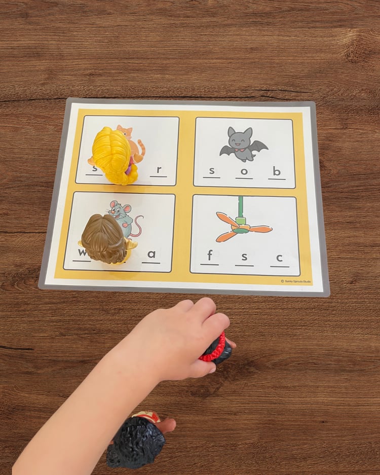 Child playing a beginner phonics game, identifying the first letter of pictures to practice letter sounds and early reading skills.