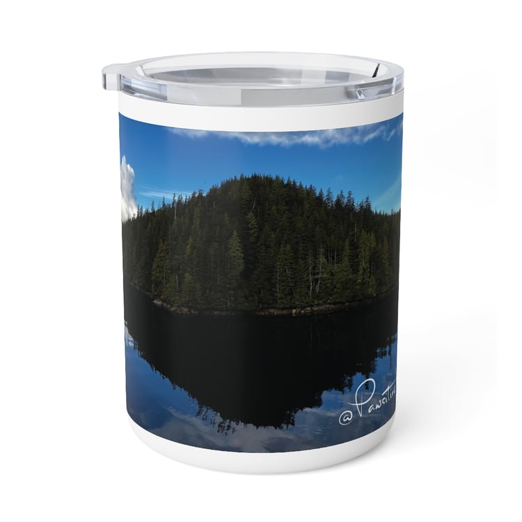 “Close‑up of insulated mug featuring sacred Alaska landscape with sky reflected on still lake.”