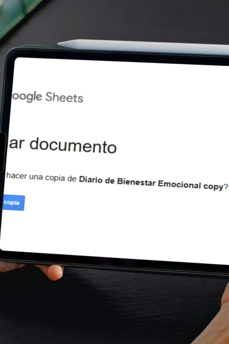 Primer plano de una tablet mostrando el mensaje de Google Sheets "¿Quieres hacer una copia de Diario de Bienestar Emocional?". Ilustra el proceso fácil de adquirir y configurar nuestras plantillas de salud y productividad personal. ✨🧠