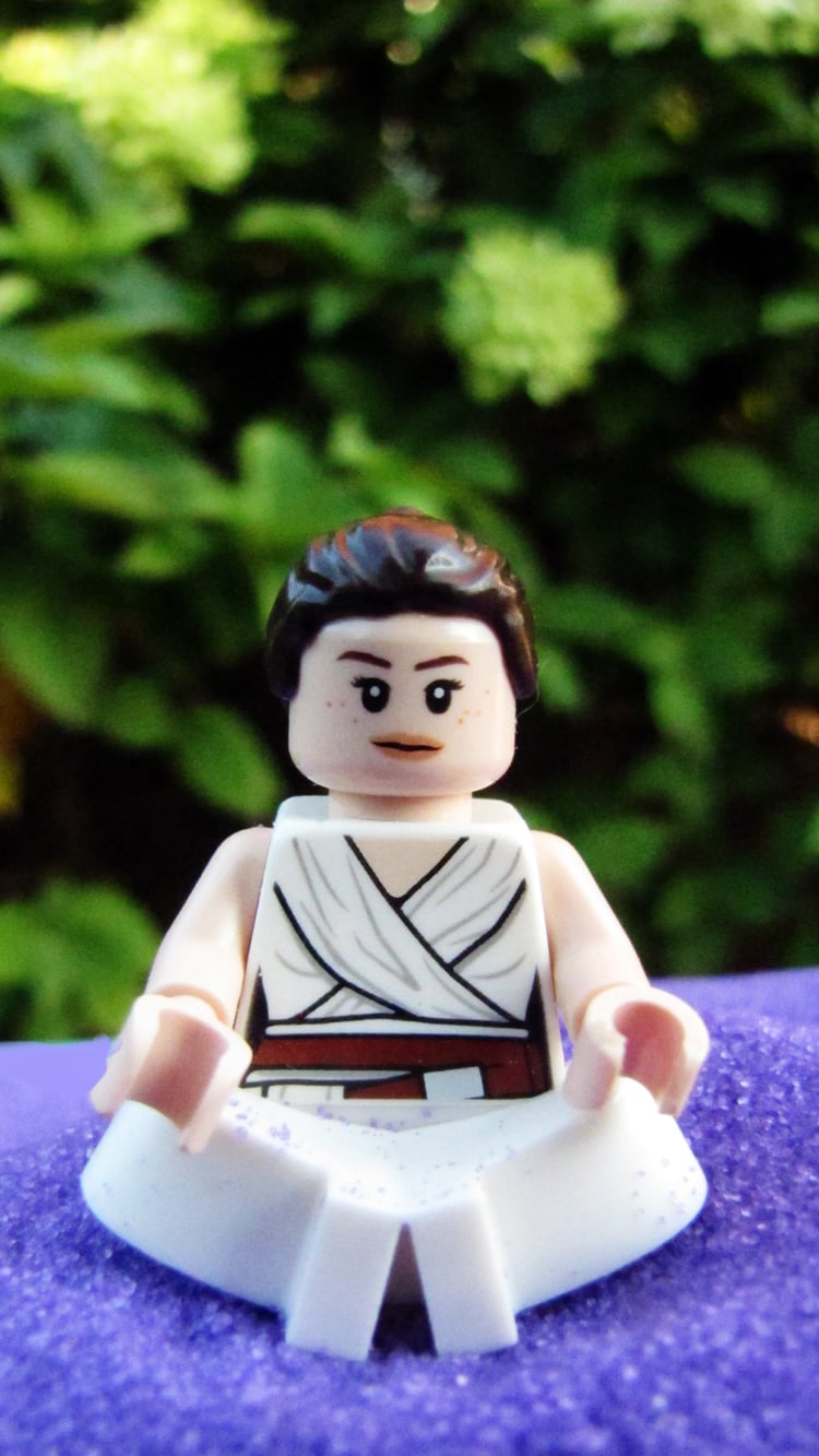 LEGO Rey is seated on purple sand. she is meditating.